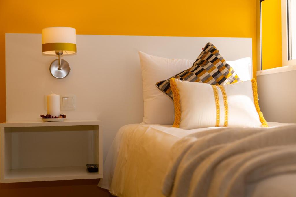 a bedroom with a bed with a yellow headboard at Chic Studios in Parede