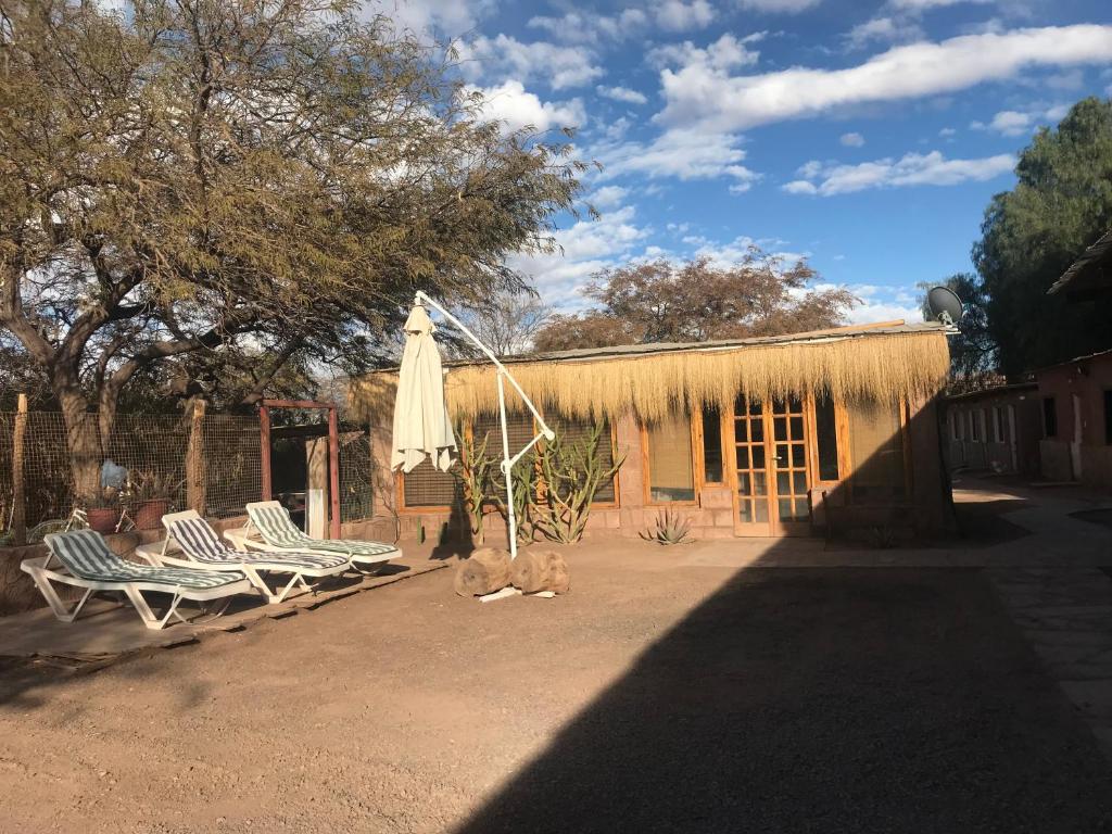 a patio with two chairs and an umbrella and a building at Quinta Adela Bed & Breakfast in San Pedro de Atacama