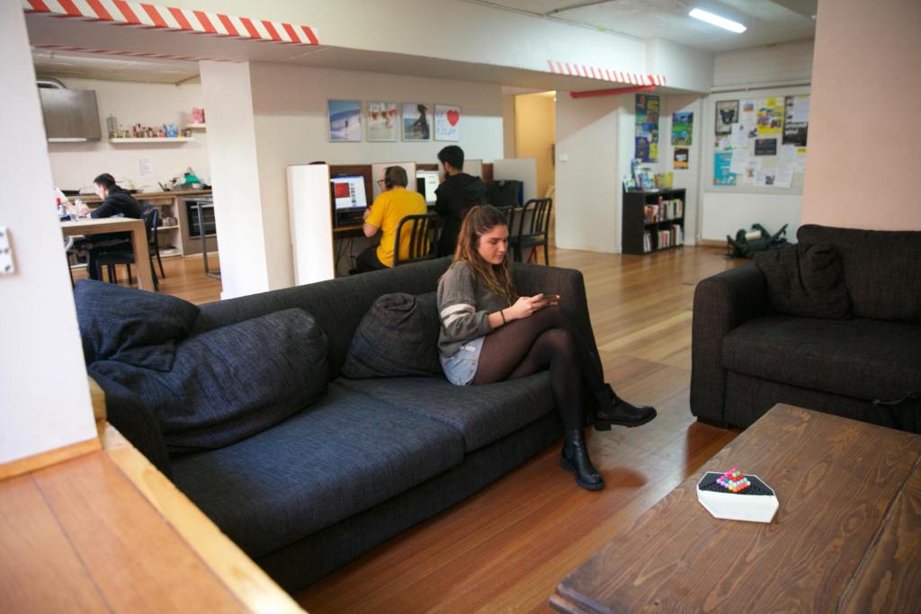 una mujer sentada en un sofá en una sala de estar en Barkly Backpackers, en Melbourne