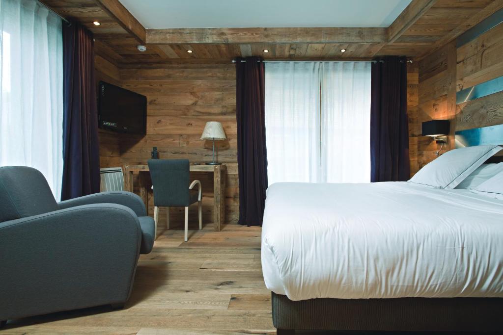 a bedroom with a bed and a chair and a table at Chalet-Hôtel La Marmotte, La Tapiaz &amp; SPA, The Originals Relais (Hotel-Chalet de Tradition) in Les Gets