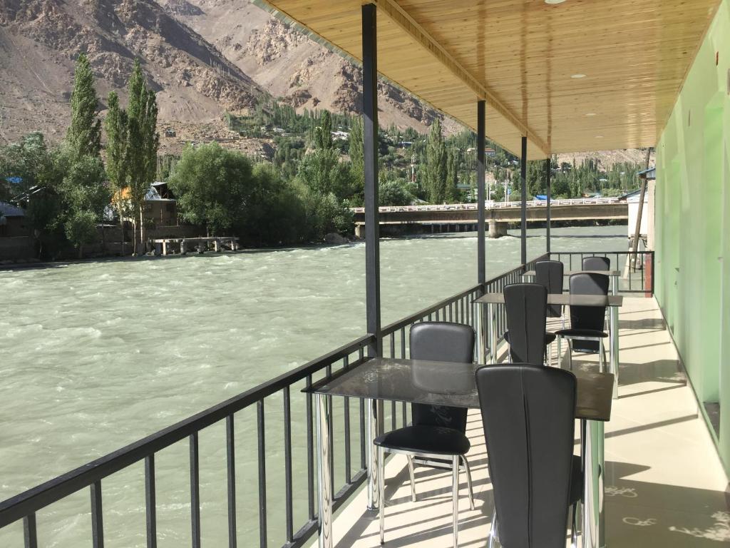 a row of chairs sitting on a balcony next to a river at Zarya Hotel in Khorog