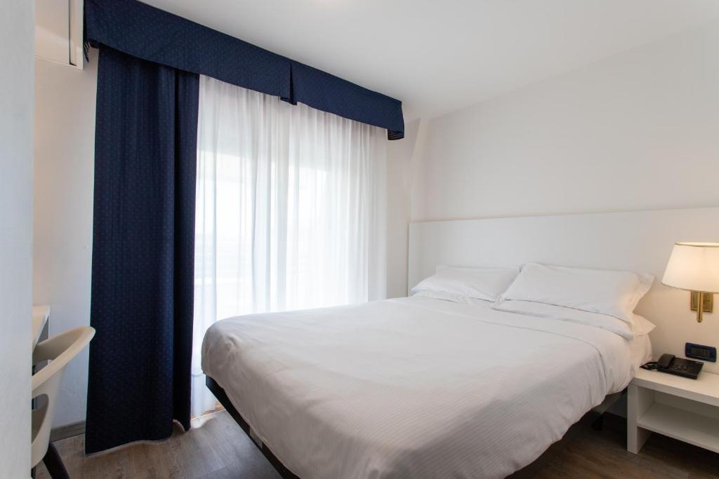 a bedroom with a large bed and a window at Fantinello Hotel in Caorle