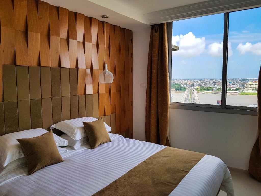 een slaapkamer met een groot bed en een groot raam bij Appartements Lamblin in Abidjan