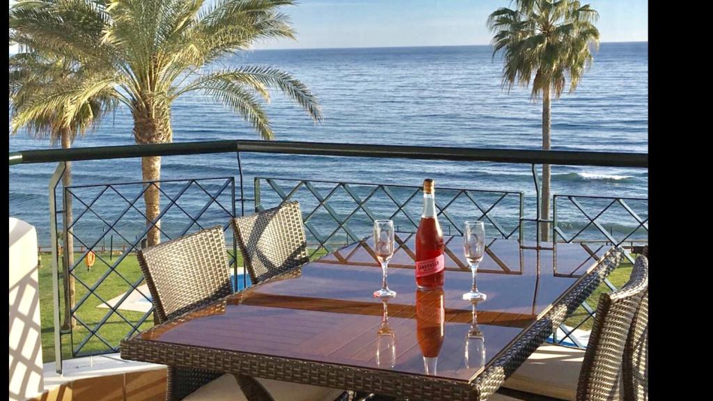 a table with wine bottles and glasses on a balcony at MI CAPRICHO A16 Beachfront Apartment in Sitio de Calahonda