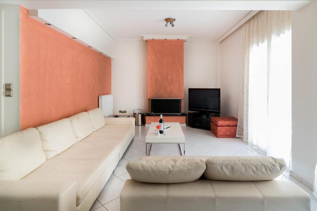 a living room with a white couch and a tv at Seaside House in Voula in Athens