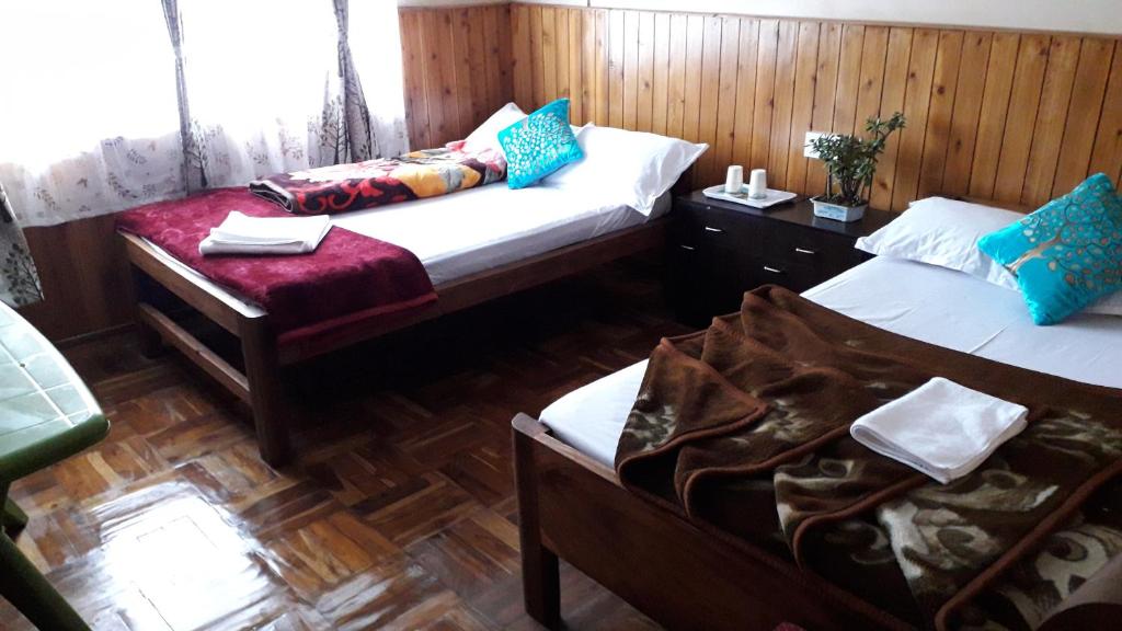Habitación con 2 camas, paredes de madera y suelo de madera. en White Tara home stay, en Darjeeling