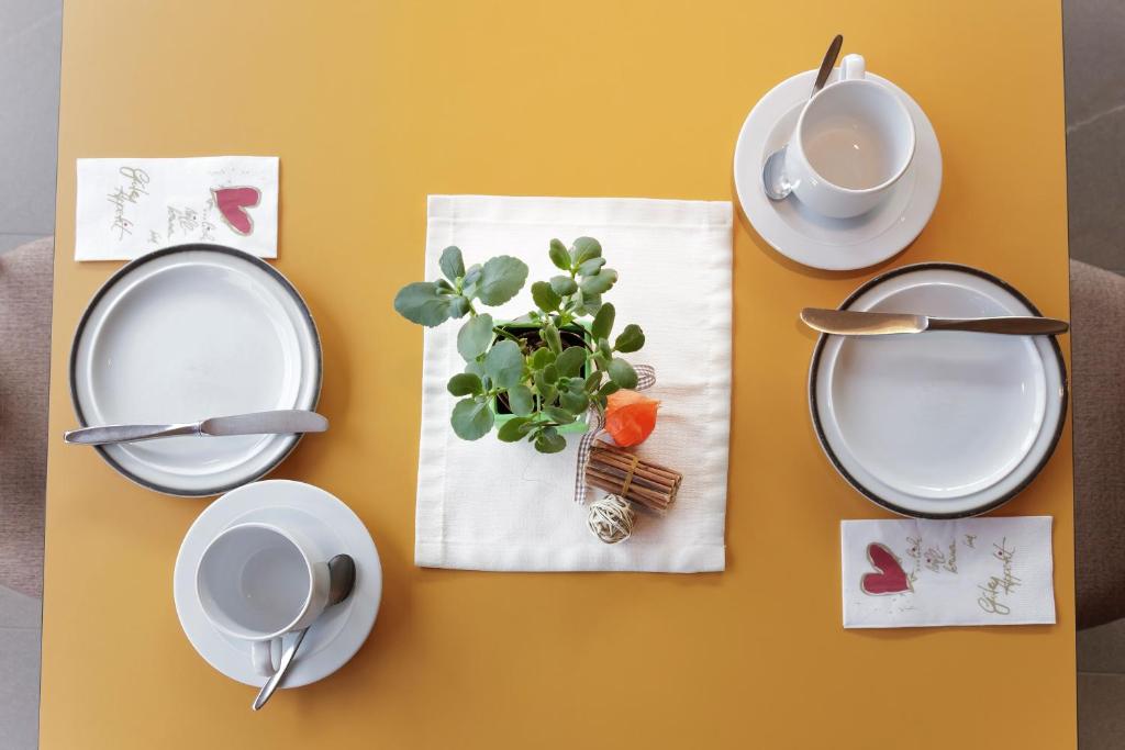 a table with plates and cups and a plant on it at Pension Waldesruh in Tarrenz