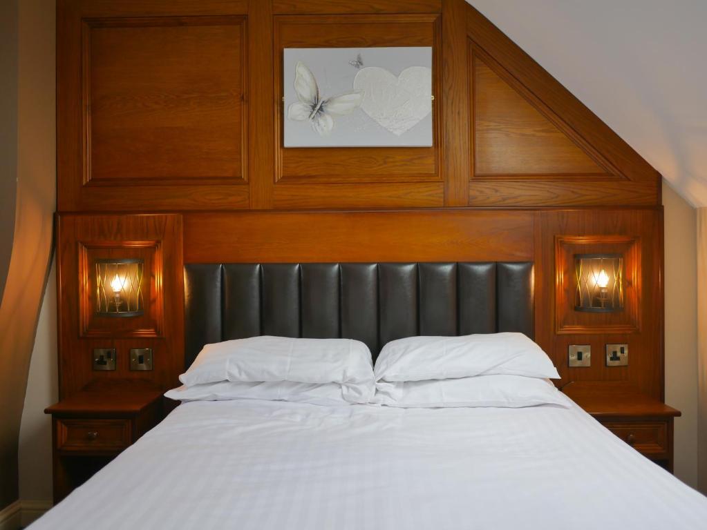 a bed with a wooden head board and white pillows at Crown & Anchor Inn in Brough