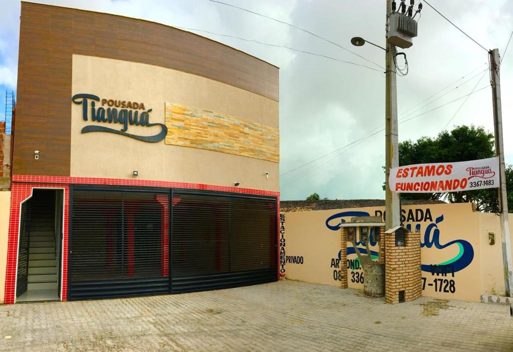 una tienda con puertas de garaje y un cartel delante de ella en Pousada Tianguá en Luis Correia