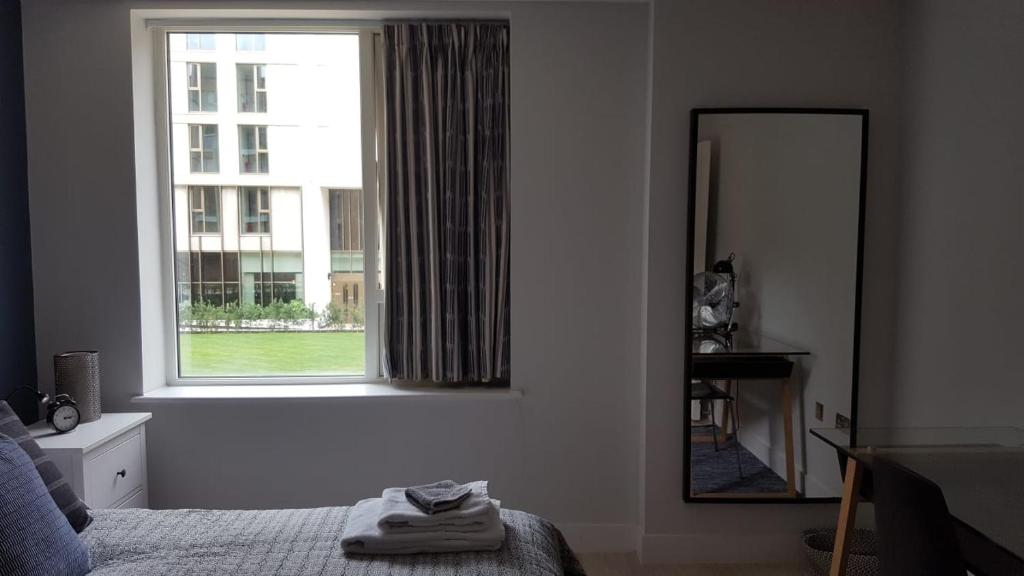 a bedroom with a bed and a mirror and a window at Great Northern Road Apartment in Cambridge