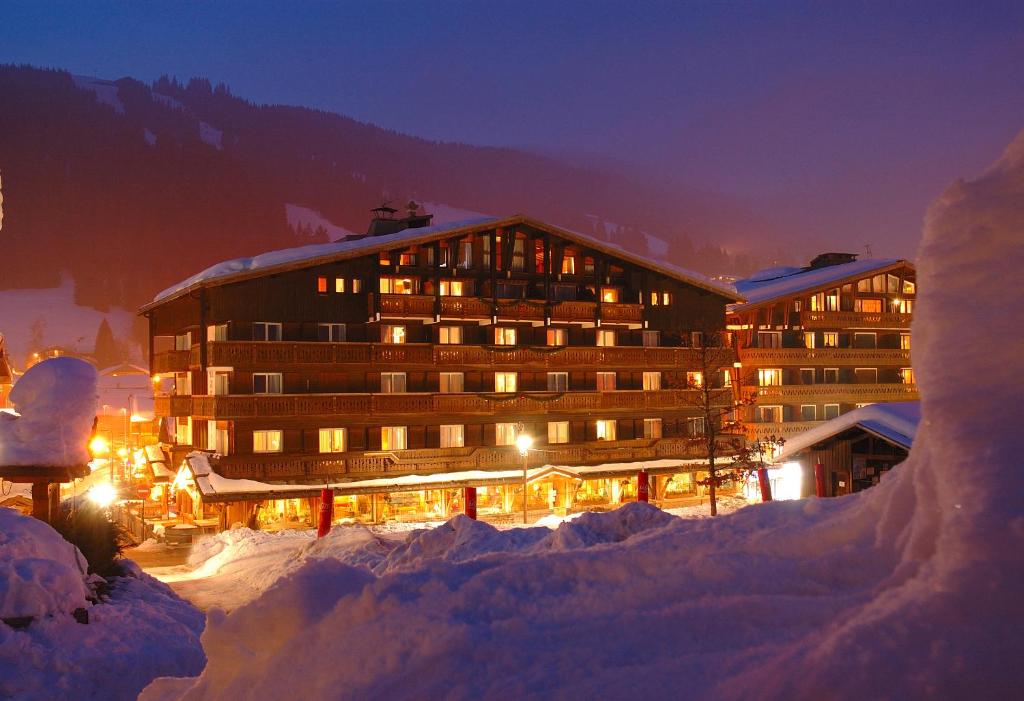 a large building in the snow at night at Chalet-Hôtel La Marmotte, La Tapiaz & SPA, The Originals Relais in Les Gets