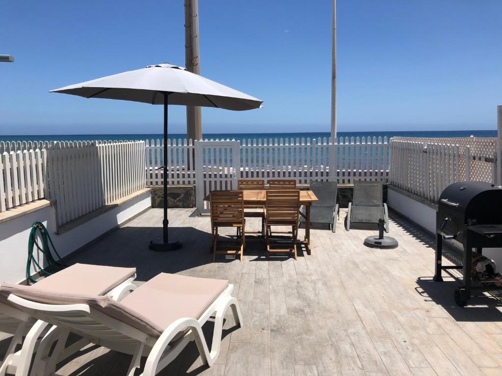 een patio met een tafel en stoelen en een parasol bij Bungalow San Agustin in San Agustin