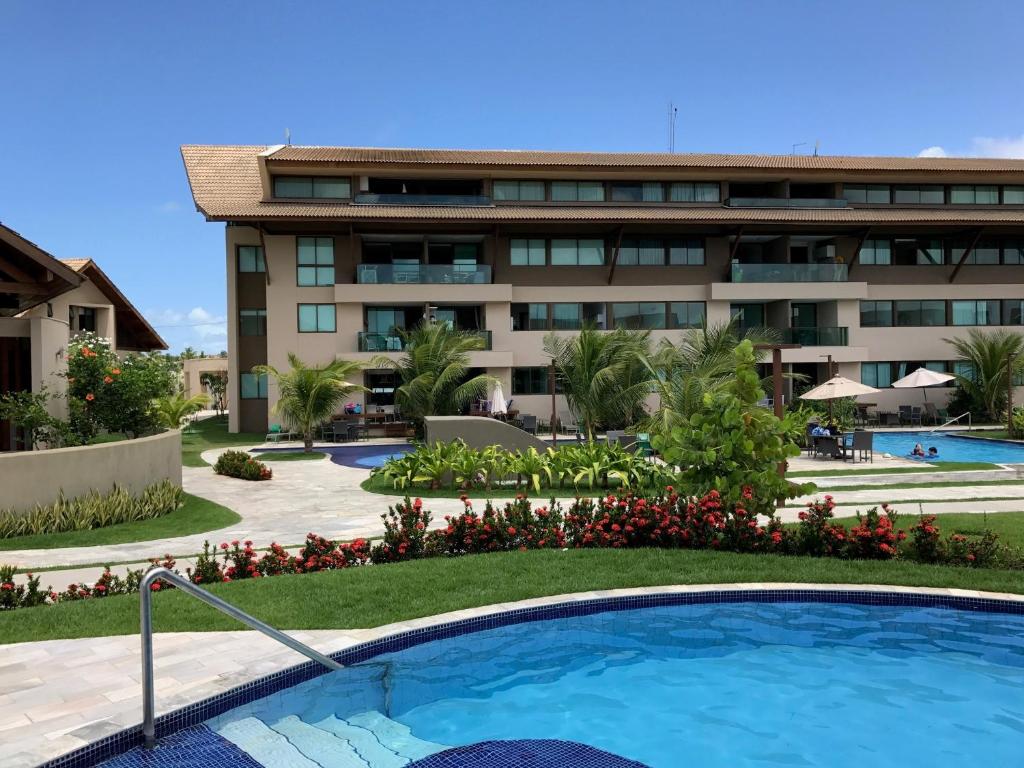 un complejo con piscina frente a un edificio en Charmoso Flat Nui Supreme - Térreo, en Porto de Galinhas