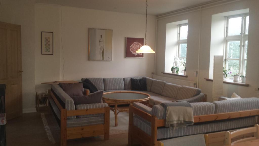 a living room with couches and a table and windows at Gamby fattiggård in Gamby