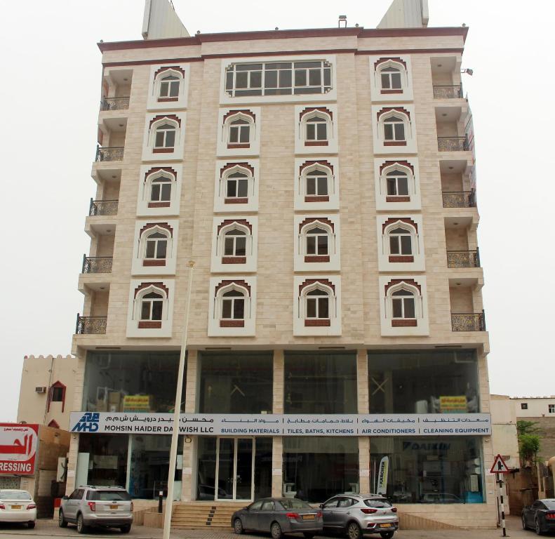 un gran edificio con coches estacionados frente a él en Al Noor Furnished Flats, en Salalah