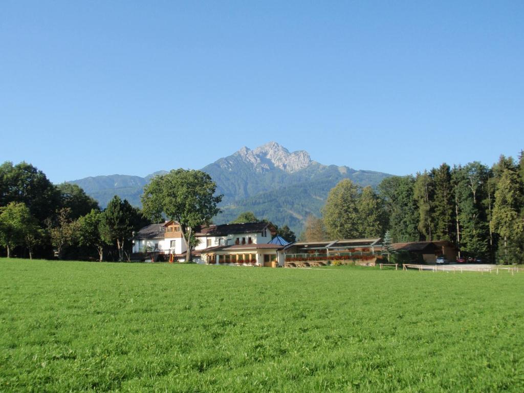 un grande campo con una casa e montagne sullo sfondo di Nattererboden a Innsbruck