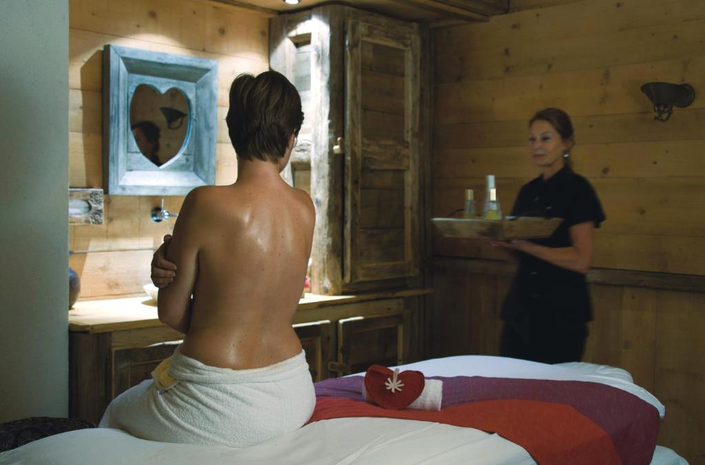 a man sitting on a bed in a room with a woman at Chalet-Hôtel La Marmotte, La Tapiaz & SPA, The Originals Relais in Les Gets