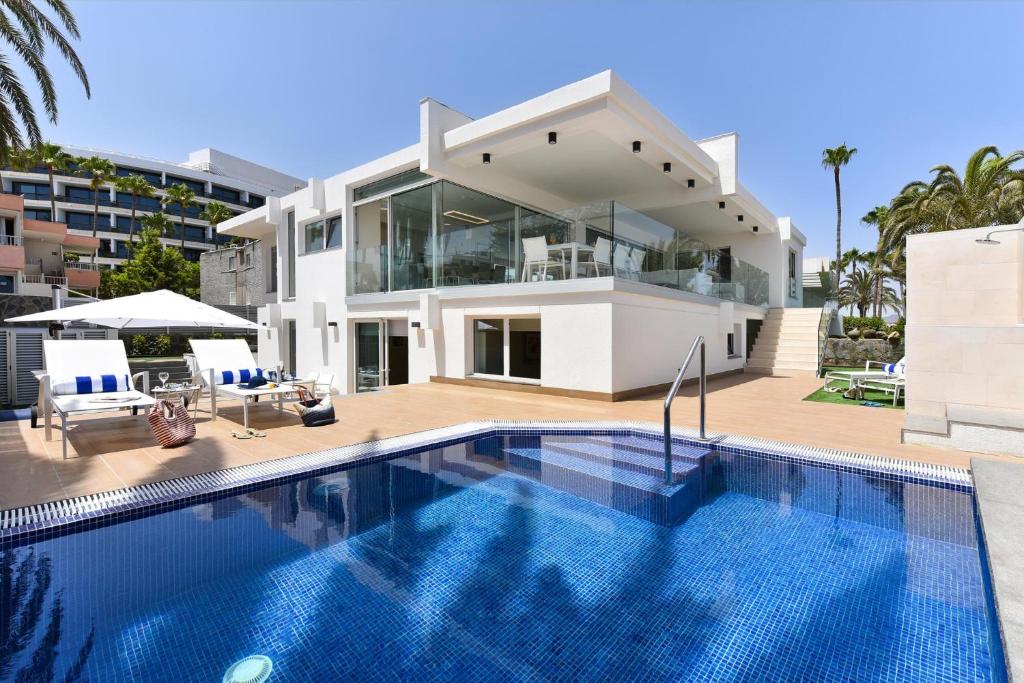a villa with a swimming pool in front of a house at Blue Ocean Villa Maspalomas in Maspalomas