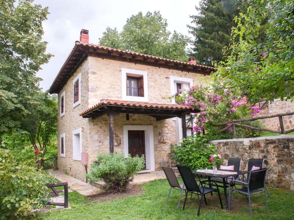 una casa de piedra con una mesa y sillas delante de ella en To Archontiko Guesthouse Villa en Stavroupoli