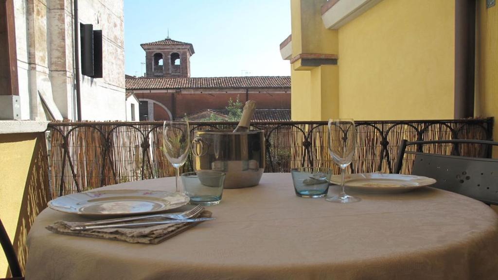 a table with plates and glasses on a balcony at Abitazione Morosini Apartment in Venice