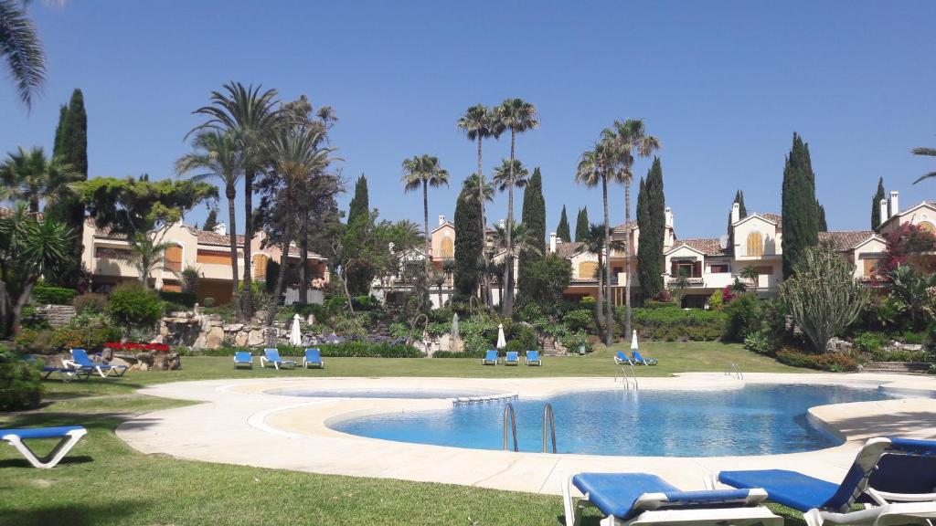 um resort com piscina, cadeiras e palmeiras em El Velerín em Estepona
