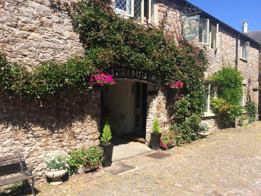 a stone building with a doorway with pink flowers at The Old Forge in Totnes