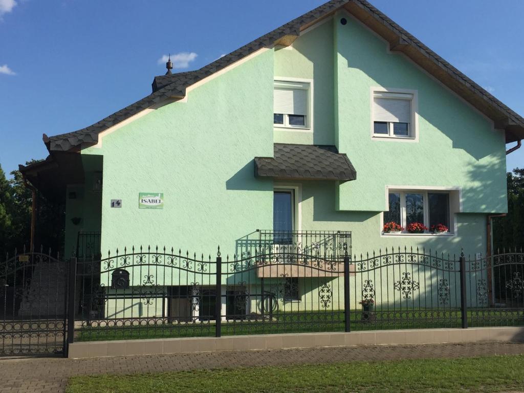 una casa verde y blanca con una valla negra en Isabel en Palić