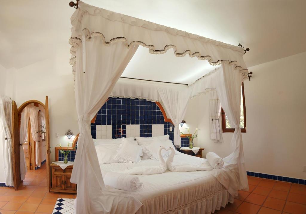a bedroom with a canopy bed with white sheets and pillows at Posada Los Alcatraces in Atlixco