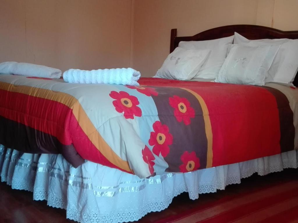 a bed with a red and white blanket on it at Casa Dorada in San Pedro de Atacama