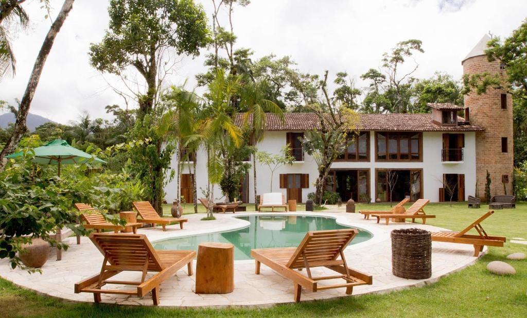a resort with a pool and chairs and a house at Estalagem Camburi in Camburi