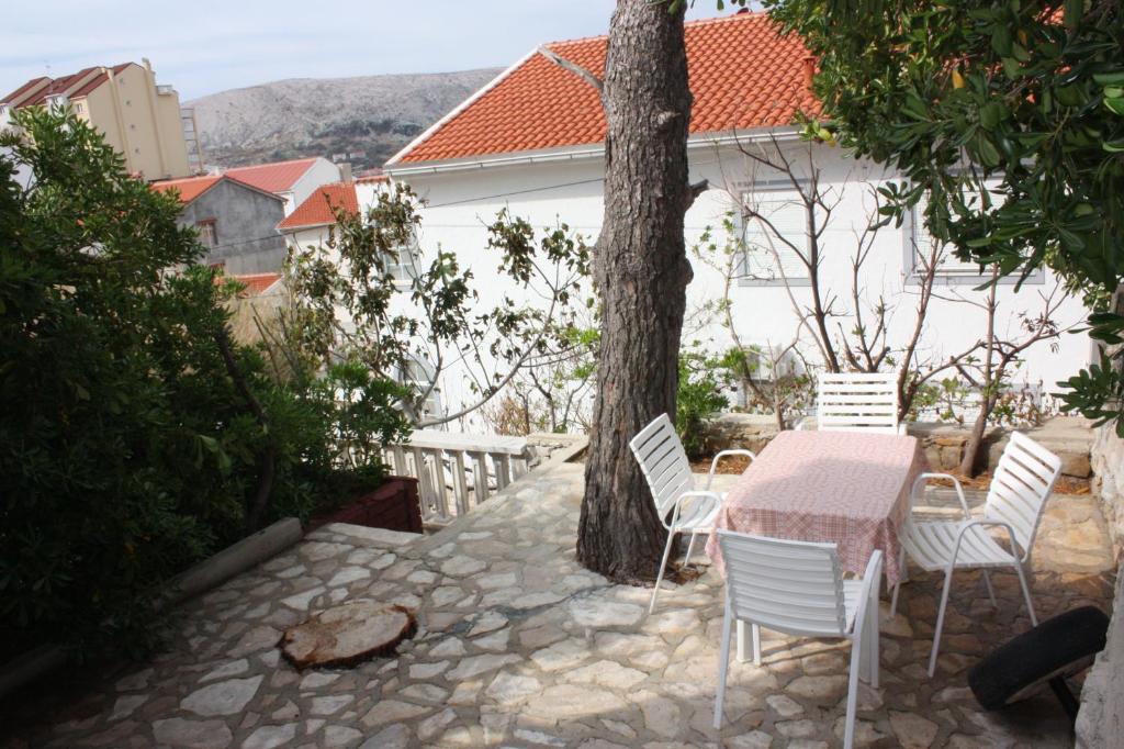 a table and chairs on a patio with a tree at Apartments Jaska in Pag