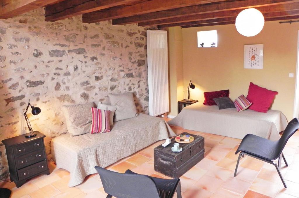 a living room with two beds and a couch at Au Son du Jardin Poitevin in Saint-Laurs