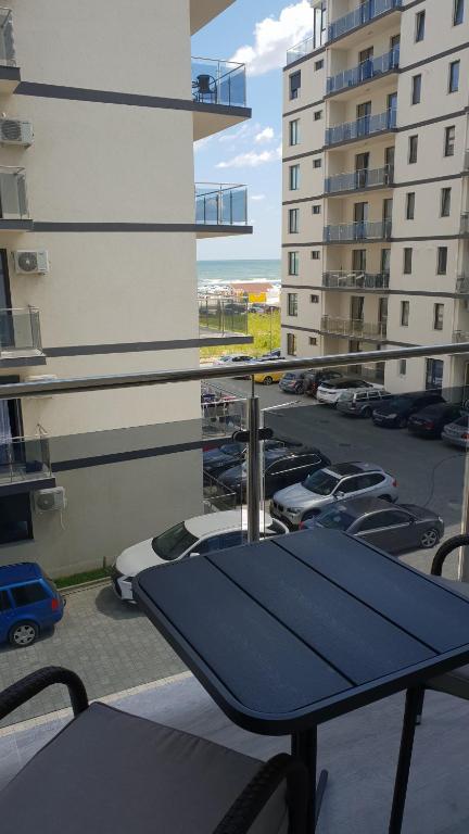 a balcony with a blue table and parked cars at Sea Sound Apartment Mamaia Nord in Mamaia Sat/Năvodari
