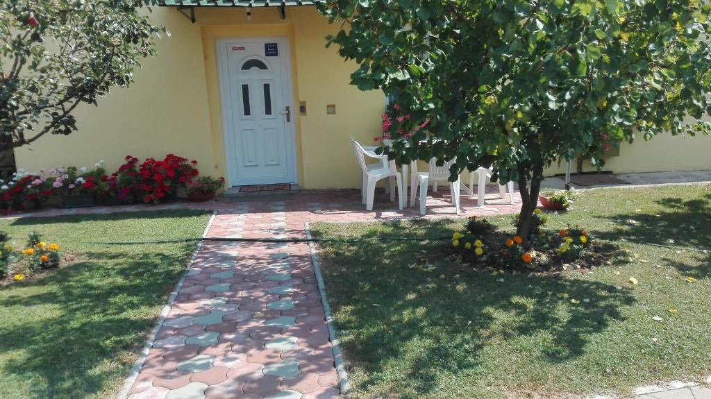 a garden with a white door and a table and chairs at Apartman Peric in Đakovo