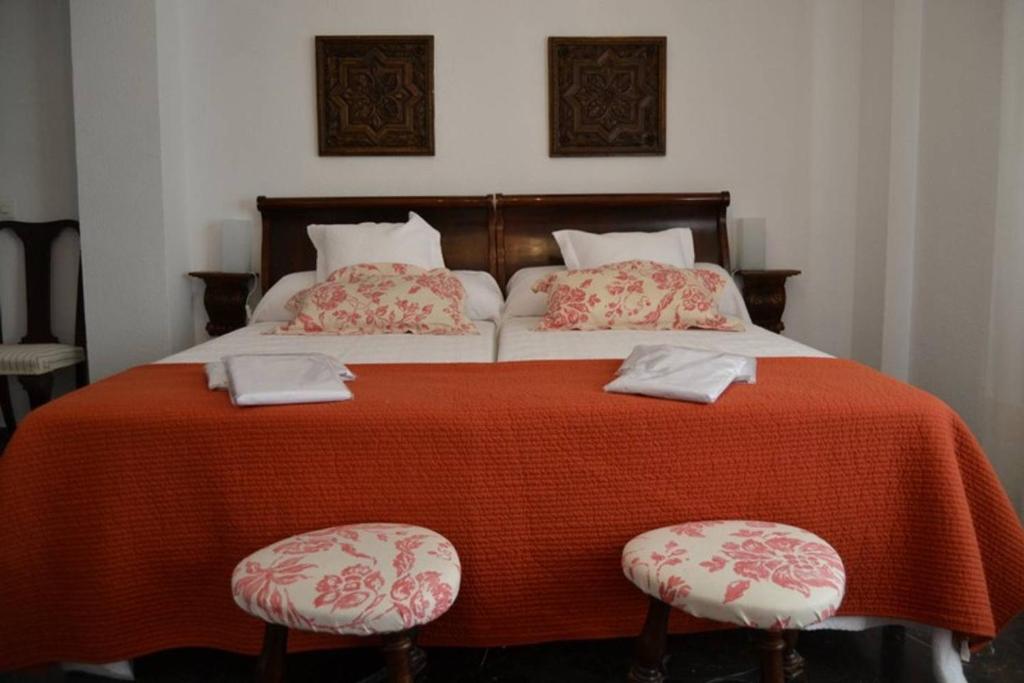 コルドバにあるPuerta de la Juderíaの大型ベッド1台(赤い毛布、椅子2脚付)