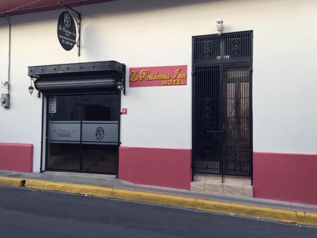 un edificio rojo y blanco con una puerta negra en La Residencia Inn, en Jinotepe