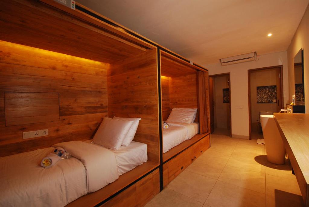 two beds in a room with wooden walls at DBeds Kuta Beach By Destiny Hospitality in Kuta