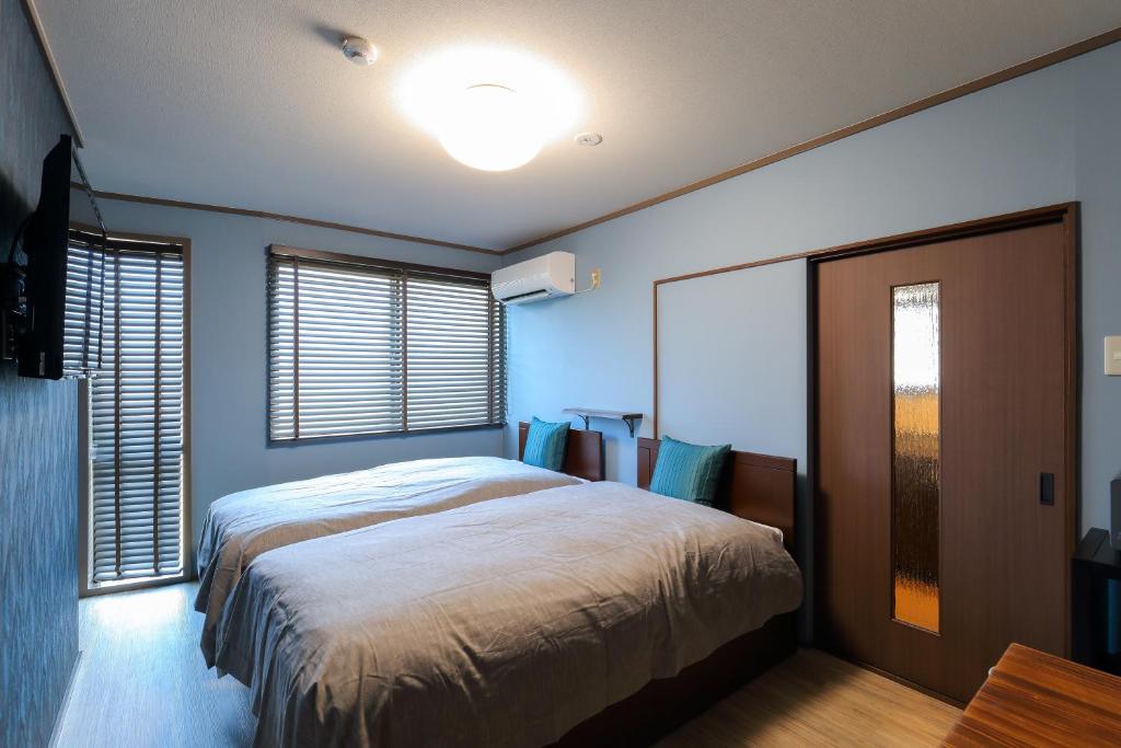 a bedroom with a large bed and two windows at Kulton Moct Kenroku in Kanazawa