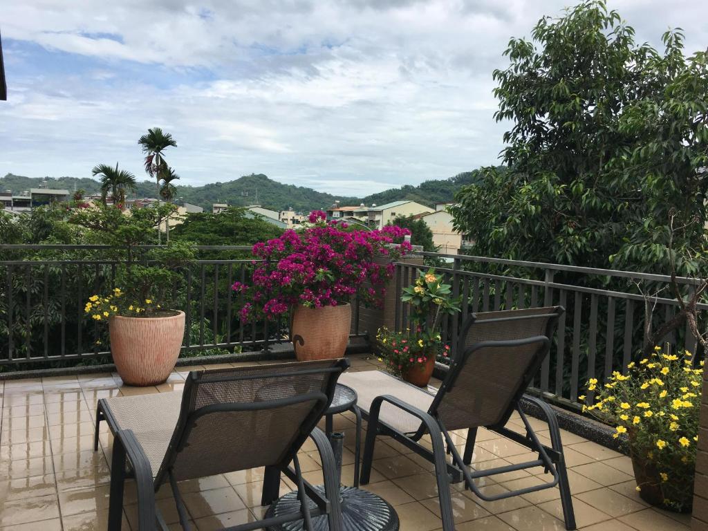 a balcony with three chairs and flowers on it at Great Nature Villa in Jiji