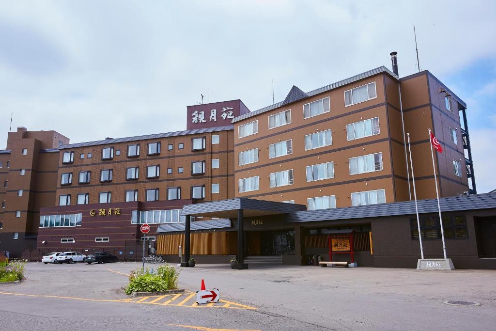 un gran edificio marrón con un estacionamiento delante de él en Kangetsuen, en Otofuke