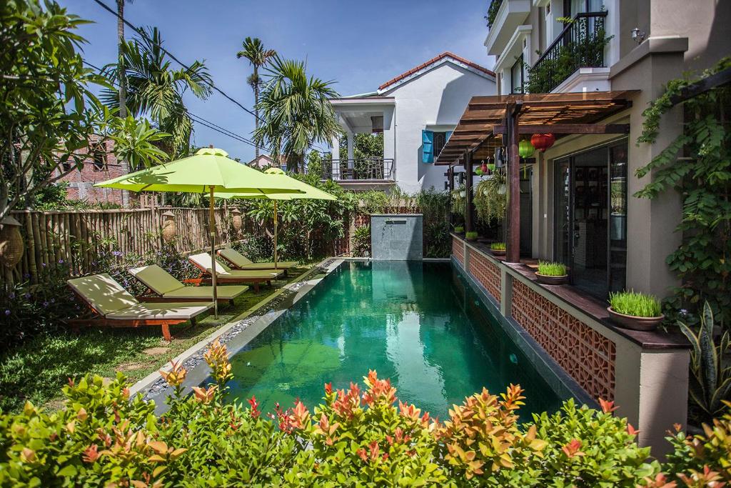 - une piscine avec un parasol en face d'une maison dans l'établissement Sông Lụa (Silk River Villa), à Hội An