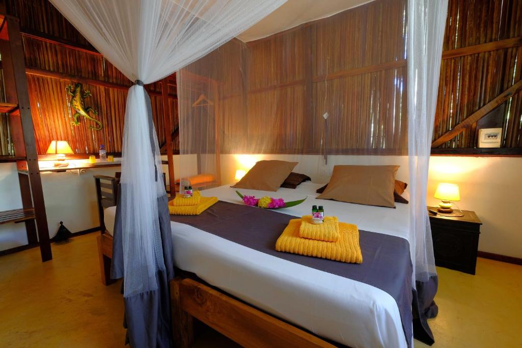 a bedroom with a bed with yellow cushions on it at Coco Komba Lodge in Nosy Komba