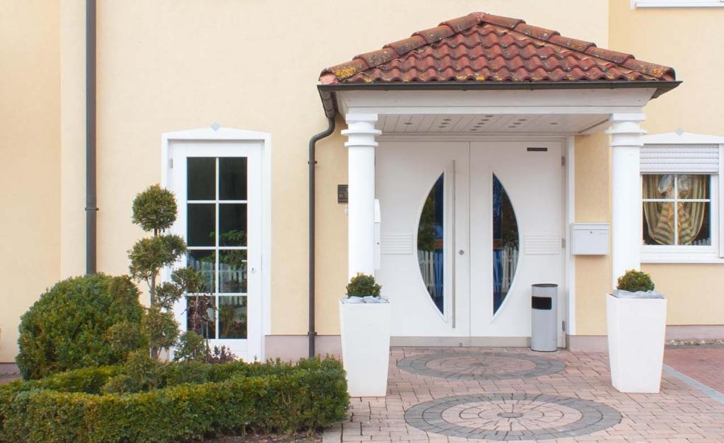 une porte d'entrée blanche menant à une maison dotée d'un toit en carrelage. dans l'établissement Hotel Waldeck Garni, à Kist