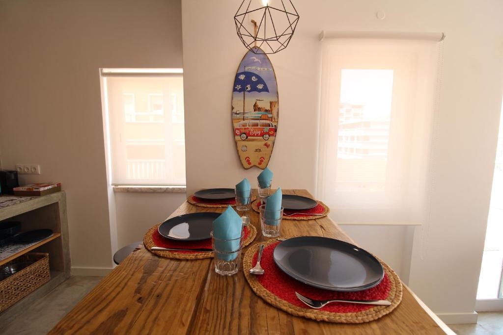 a table with plates and a surfboard on the wall at House Beach in Costa da Caparica