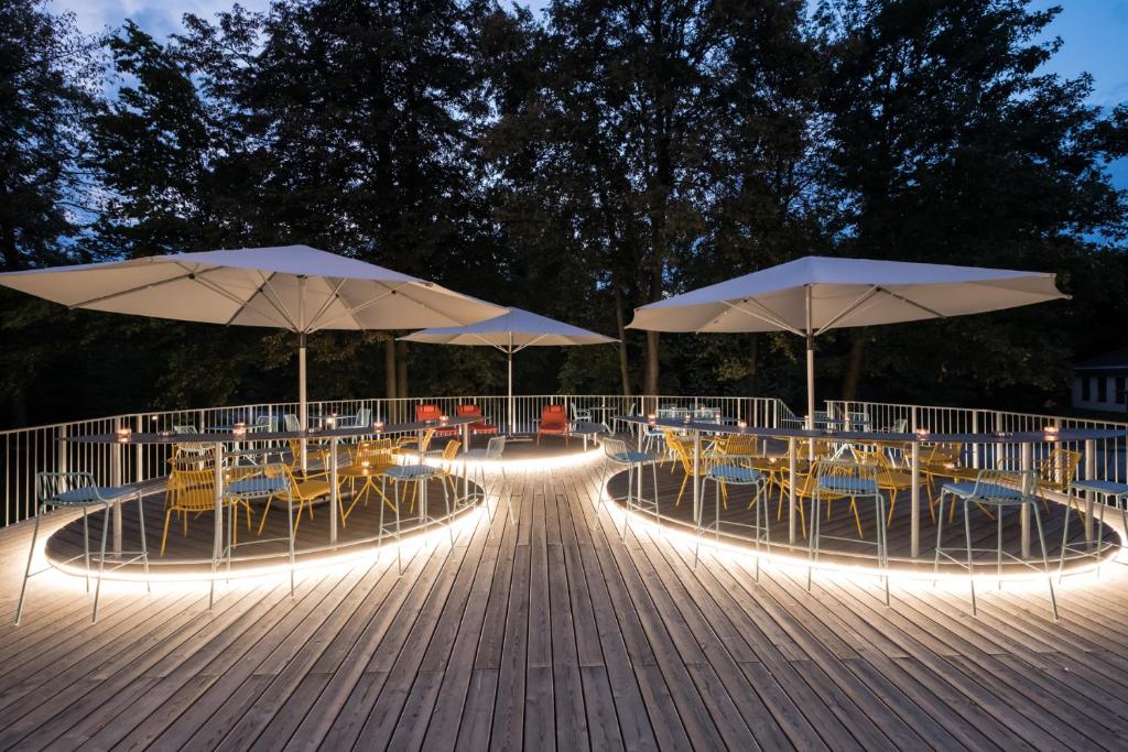 two tables and chairs with umbrellas on a wooden deck at Airbase Hotel in Kalsdorf bei Graz