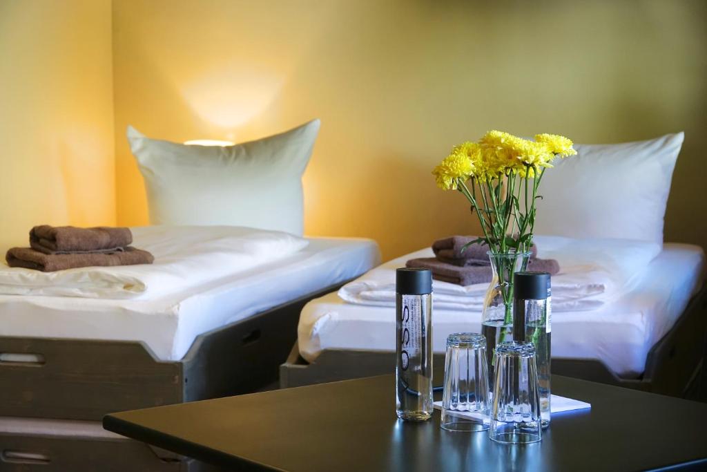 クヴェードリンブルクにあるHostel & Hotel Samoccaのベッド2台と花のテーブルが備わる客室です。