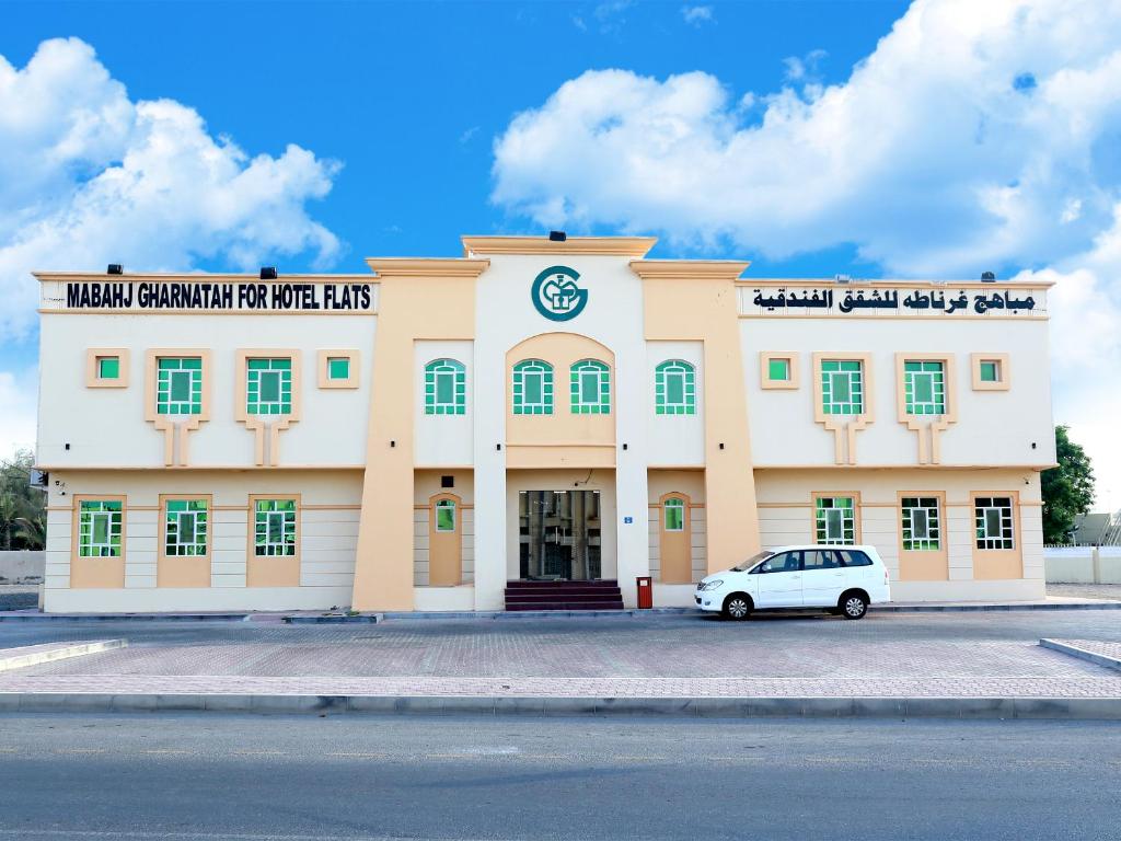 a building with a car parked in front of it at Mabahj Garnatha Hotel Apartments in Sohar