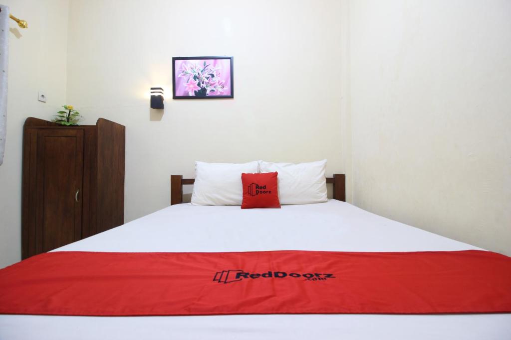 um quarto com uma cama com um cobertor vermelho em RedDoorz @ Jalan Parangtritis em Yogyakarta