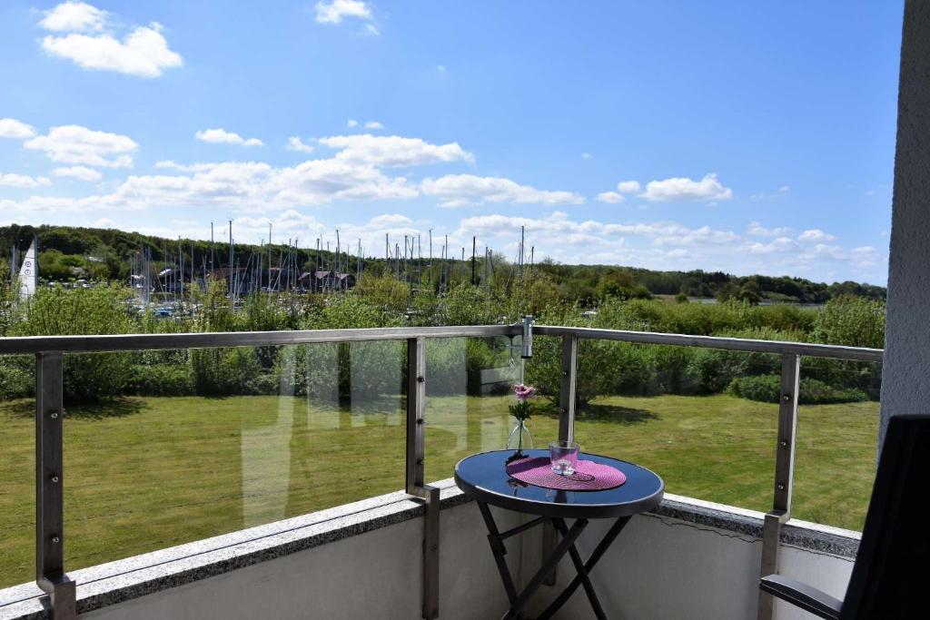 a table on a balcony with a view of a field at Freiwasser Appartment in Glücksburg