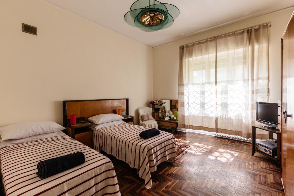 sypialnia z 2 łóżkami, telewizorem i oknem w obiekcie Casa Sole Luna con giardino by Wonderful Italy w mieście Palermo